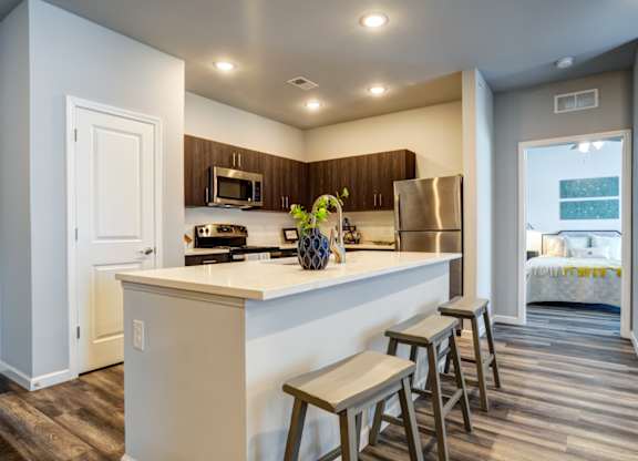 A kitchen with a white counter top and wooden floors.