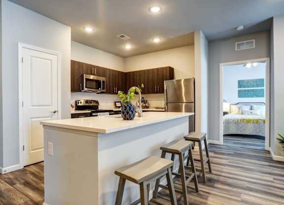 A kitchen with a white counter top and wooden floors.
