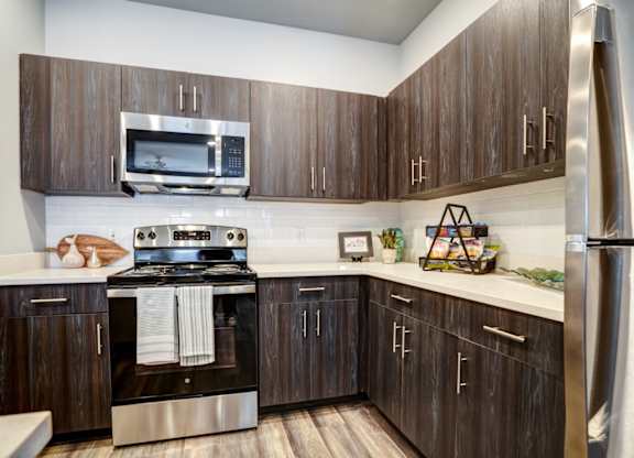 A modern kitchen with dark wood cabinets and stainless steel appliances.