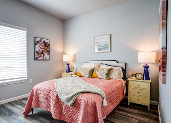 A bedroom with a bed, nightstands, and a window.