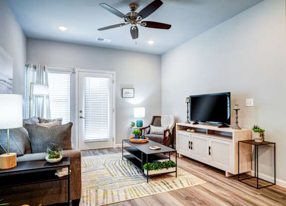 A living room with a ceiling fan, a couch, a coffee table, and a television.
