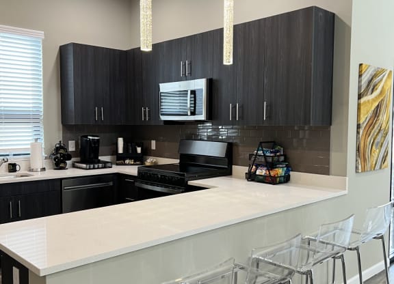 a kitchen with black cabinets and a bar with chairs