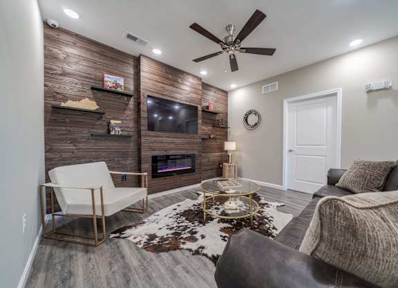 A modern living room with a white chair, a grey couch, and a wooden wall.