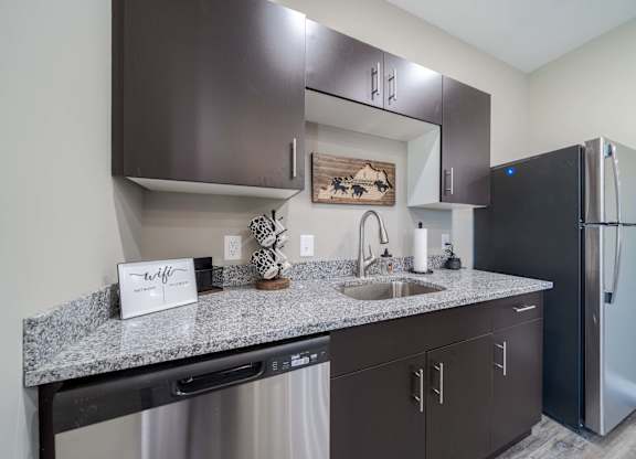A kitchen with dark brown cabinets and a black refrigerator.