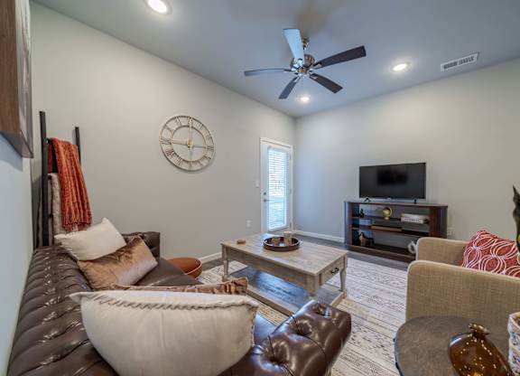 A living room with a brown leather couch and a white bean bag chair.
