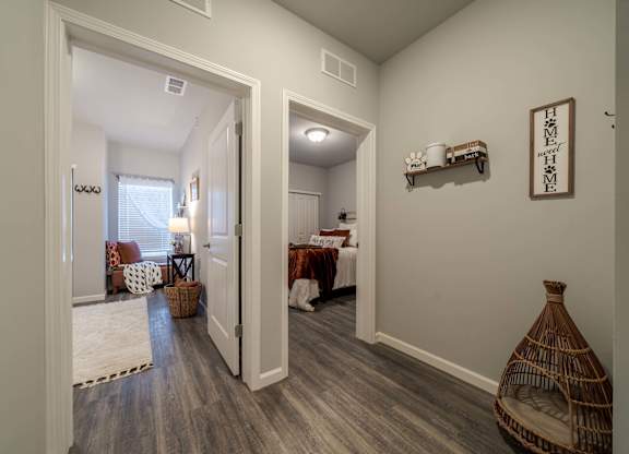 A hallway with a wooden floor and a wall shelf with a sign that says "Home Sweet Home".
