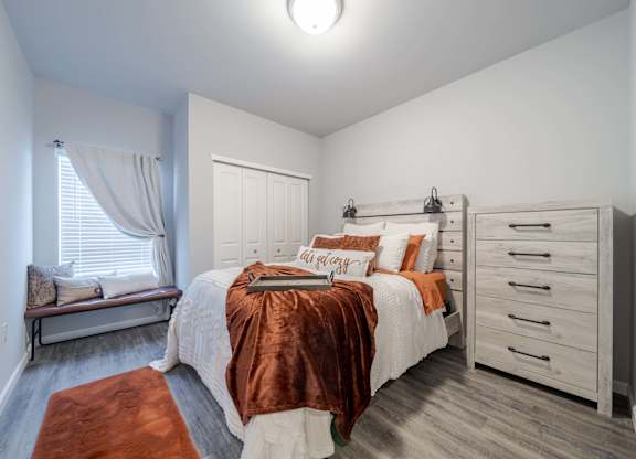 A bedroom with a bed, dresser, and window.