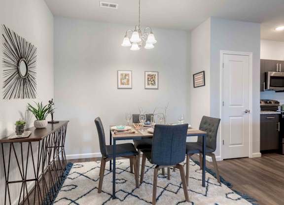 A dining room with a table set for two and a kitchen in the background.