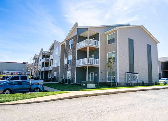 the exterior of an apartment building with cars parked in front