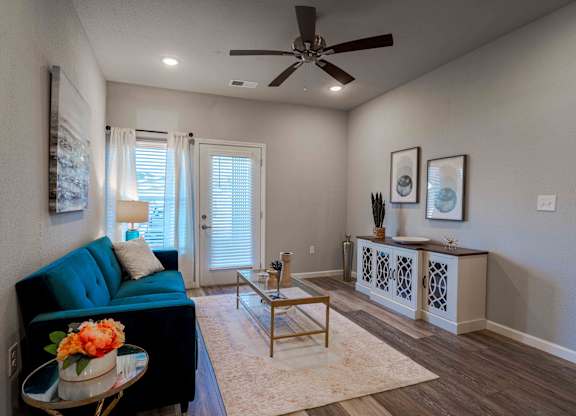 a living room with a blue couch and a ceiling fan