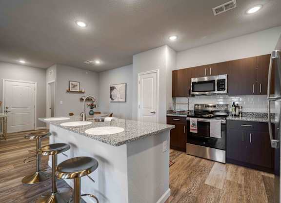 a kitchen with stainless steel appliances and a counter with stools