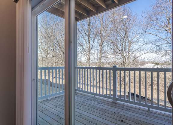 A view from inside a house looking out to a deck with a white railing.