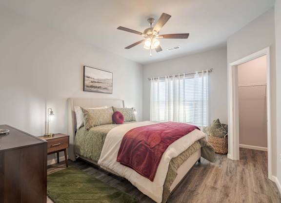 A bedroom with a bed, nightstand, and a ceiling fan.