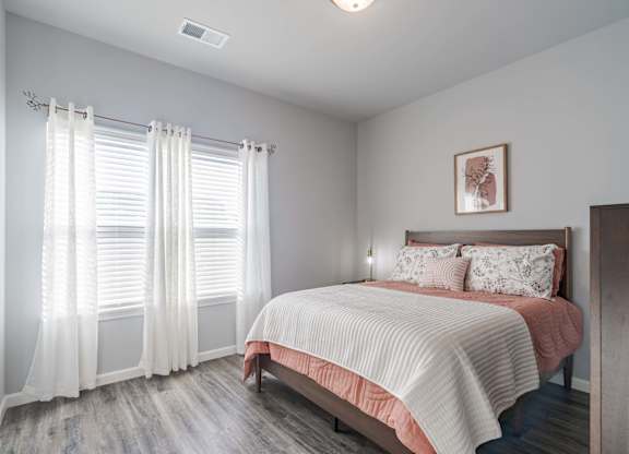 A bedroom with a bed, pillows, and a window with curtains.