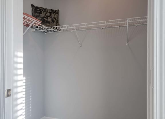 A white closet with a pillow on a shelf.