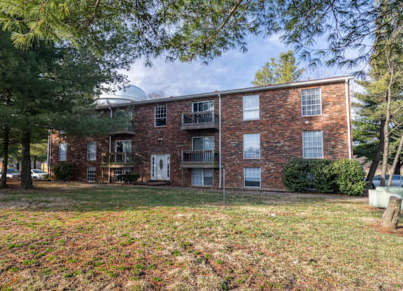 A brick apartment building with a green lawn in front.