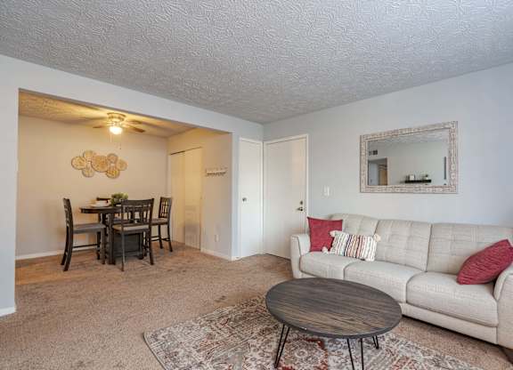 A living room with a couch, a dining table, and a rug.