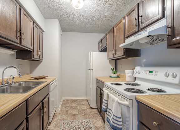 A kitchen with wooden cabinets and a white stove top oven.