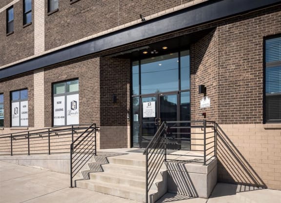 the front of a brick building with stairs and a glass door