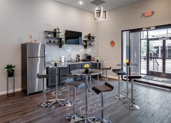 a kitchen area with bar stools and a counter with a refrigerator