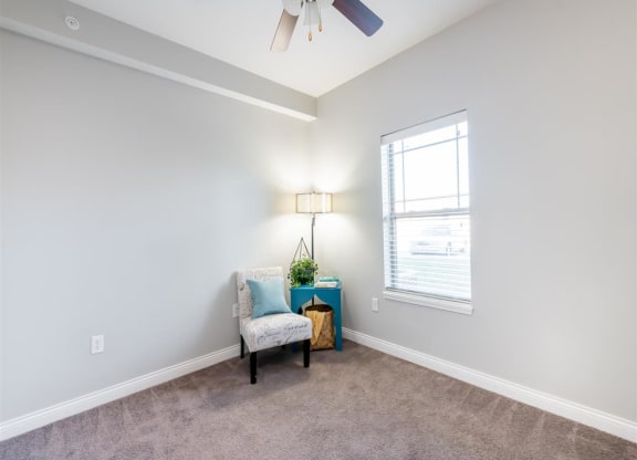 a living room with a chair and a ceiling fan