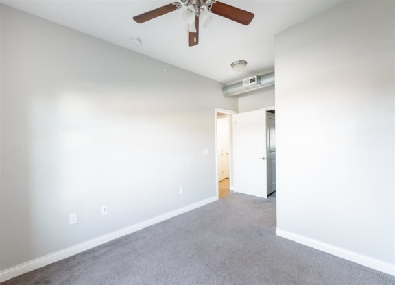 an empty living room with a ceiling fan and white walls