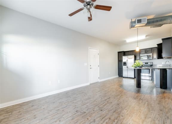 an empty living room and kitchen with a ceiling fan