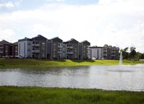 a pond with a fountain in front of an apartment building
