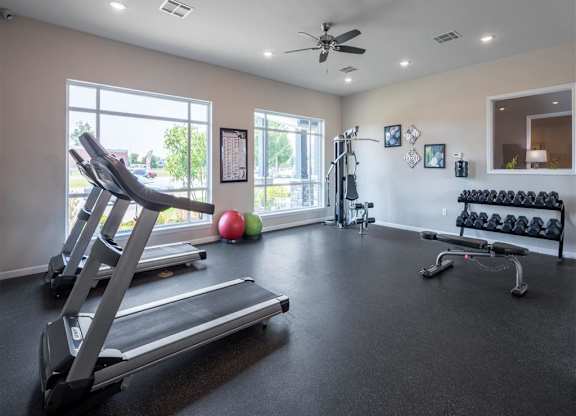 a gym with treadmills and balls on the floor