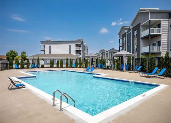 a resort style pool with blue chairs and a building in the background