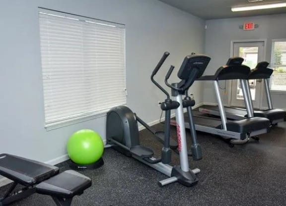 a gym with exercise equipment and a green ball