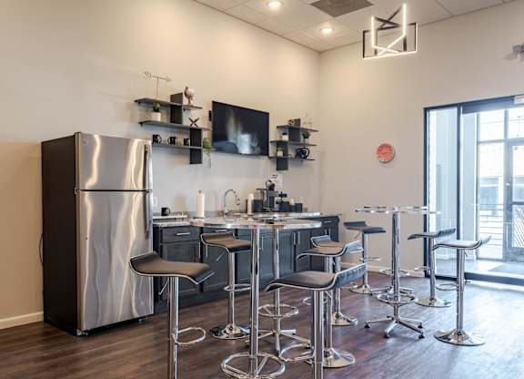 A modern kitchen with a large stainless steel refrigerator and matching bar stools.