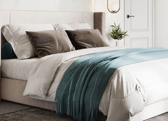 A bed with a white comforter and a blue blanket is in the center of the image.