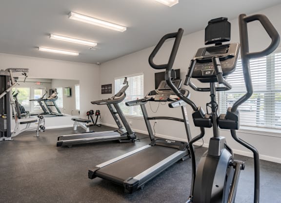a gym with cardio equipment on the floor and a large window