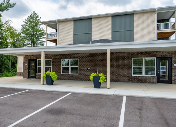 the front of a brick apartment building with a covered parking lot
