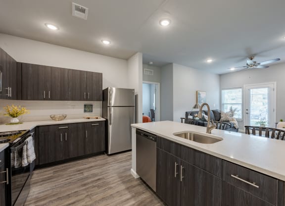 an open kitchen and living room with a stainless steel refrigerator