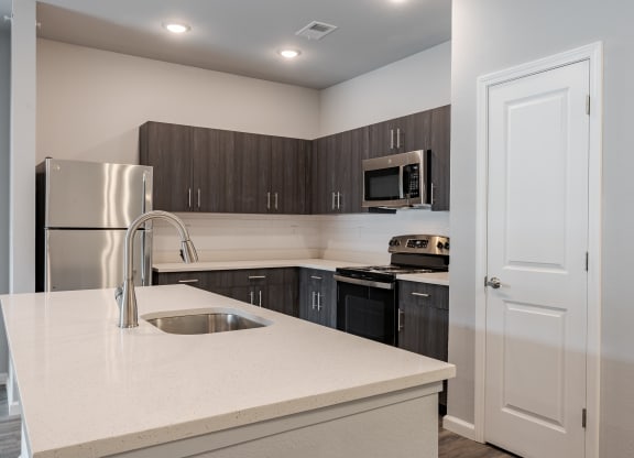 a kitchen with a white counter top and a stainless steel refrigerator