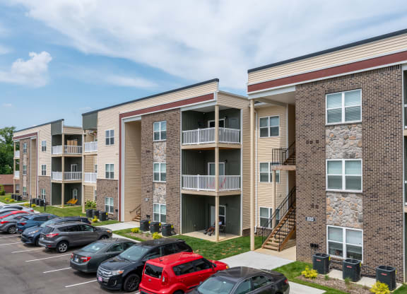 an exterior view of an apartment building with cars parked in a parking lot