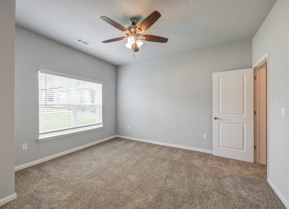 an empty room with a ceiling fan and a window