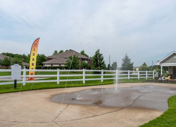 a fountain in a park with houses in the background