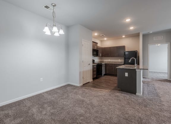an empty living room with a kitchen in the corner