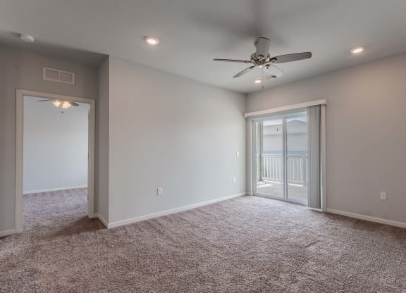an empty room with a ceiling fan and a door to a balcony