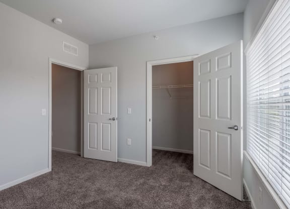 an empty bedroom with two doors and a closet