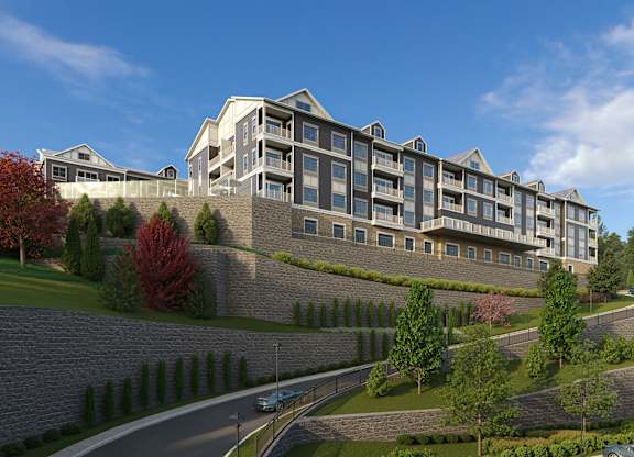 A large building with a grey stone wall in front of it.