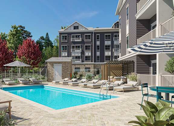 A pool surrounded by chairs and trees in front of a building.