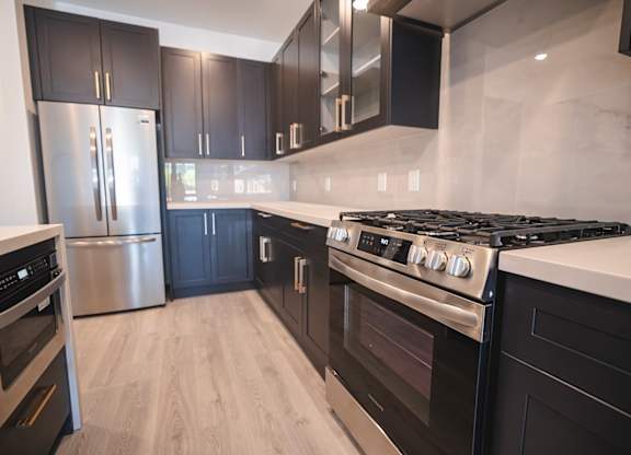 A modern kitchen with black cabinets and stainless steel appliances.at The Franklin at Westfield, Westfield, 07090