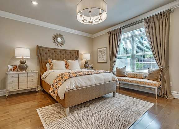 A bedroom with a large bed and a bench by the window.