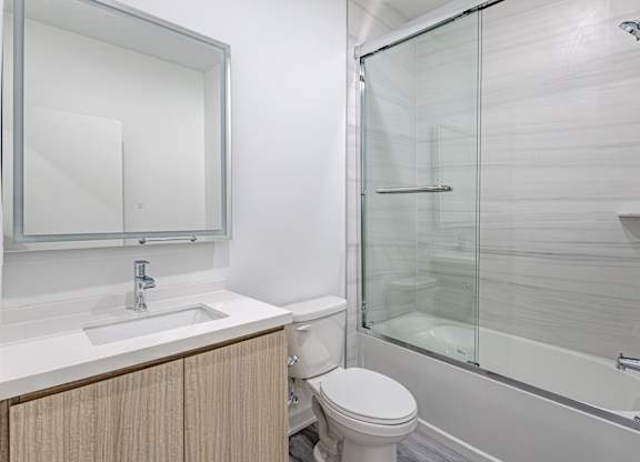 A white bathroom with a toilet, sink, and shower. at The Franklin at Marlboro, New Jersey, 07746