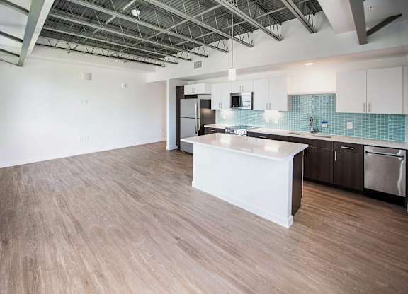 A kitchen with a white island and wooden floors at Elements on Third Apartments, St. Petersburg, FL, 33713