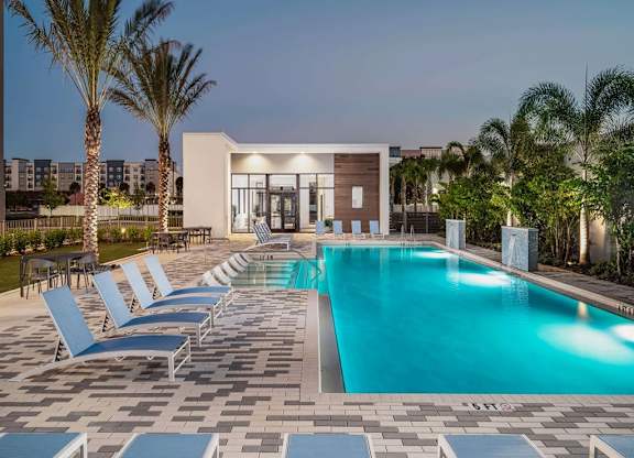 a swimming pool with lounge chairs and palm trees at Elements on Third Apartments, Florida